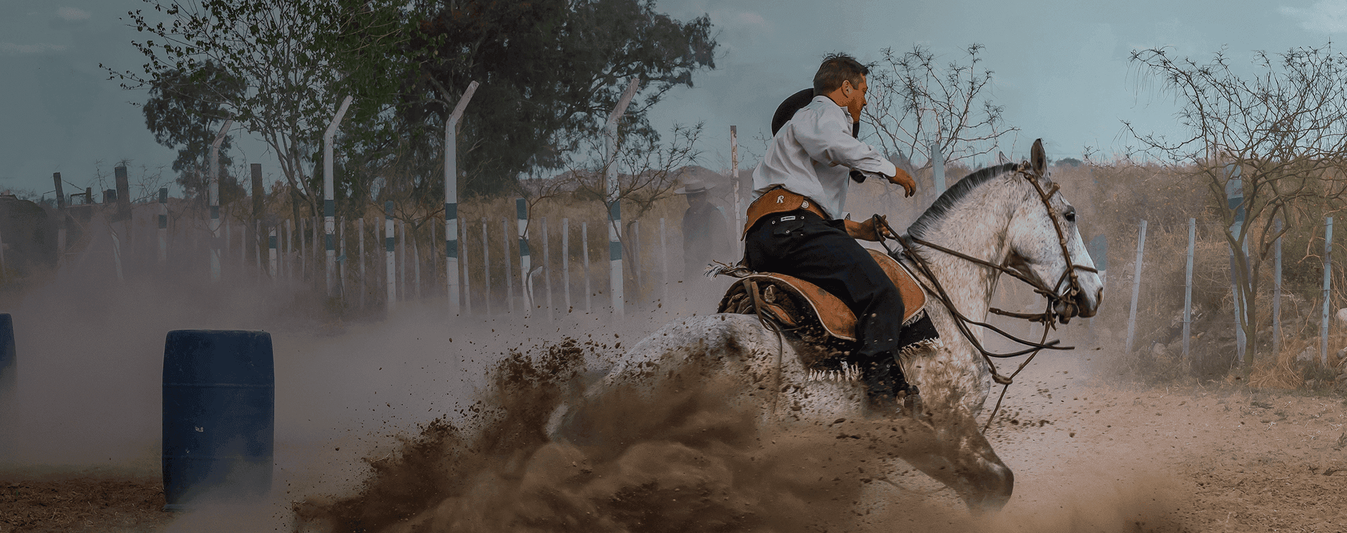 Horseback rider in traditional gaucho attire kicks up dust as he makes a turn. Overlaid is the Spanish word "gaucho" with its English translation, "skilled horseman".
