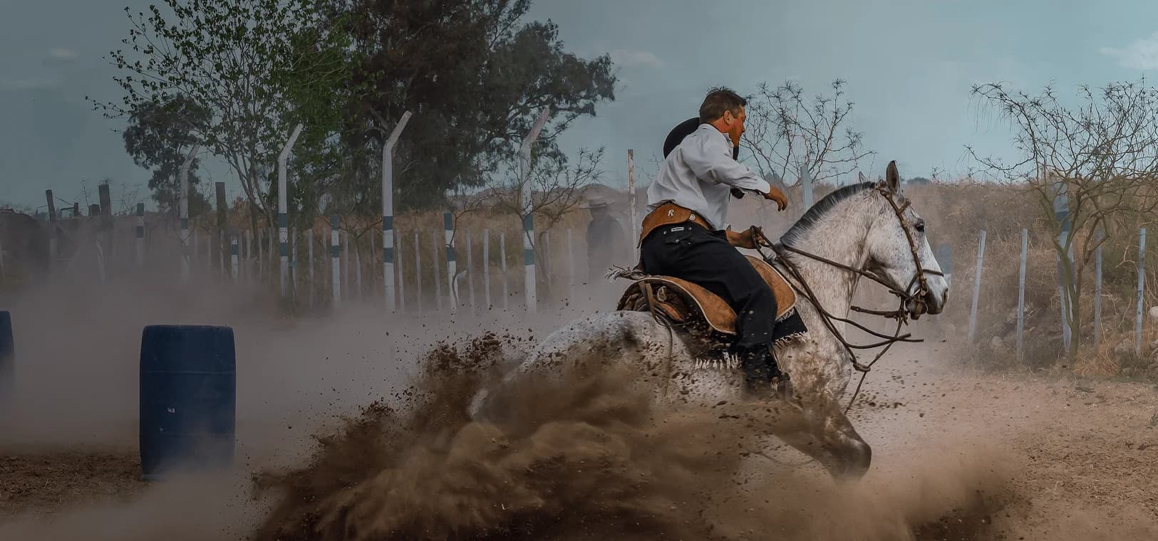 Horseback rider in traditional gaucho attire kicks up dust as he makes a turn. Overlaid is the Spanish word "gaucho" with its English translation, "skilled horseman".