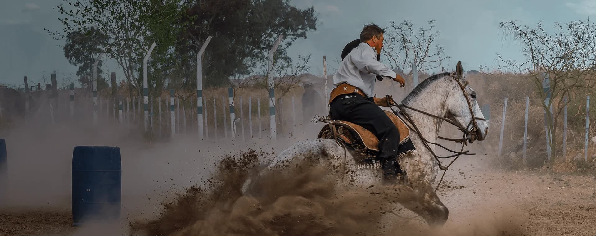 Horseback rider in traditional gaucho attire kicks up dust as he makes a turn. Overlaid is the Spanish word "gaucho" with its English translation, "skilled horseman".